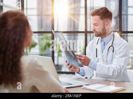 Concentrated male doctor looking at x-ray picture of spine Stock Photo