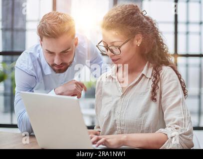 Colleagues check documents using a laptop. A man and a woman are sitting together looking at a laptop. business concept Stock Photo