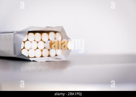 Full open pack of cigarettes stands on glossy tabletop, white background, side view. Stock Photo