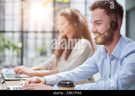 Handsome male customer service agent working in call center office as a telemarketer. Stock Photo