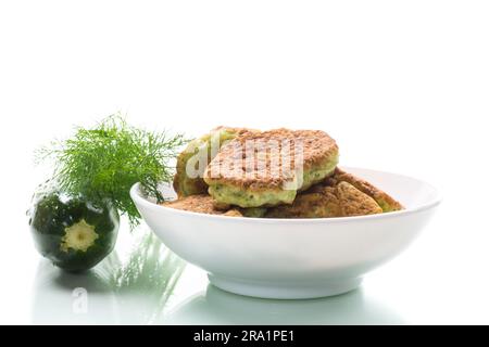 fried zucchini pancakes with herbs, in a plate isolated on a white background. Stock Photo