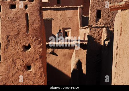 African man Talking on cellphone amongst clay buildings in Morocco Stock Photo