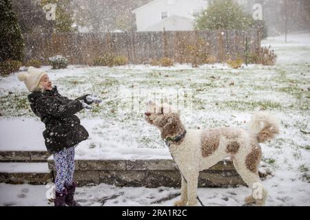 little girl playing with big dog outside in the snow together smiling Stock Photo