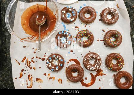 Overhead view of homemade donuts and chocolate on kitchen counter Stock Photo