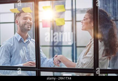 Business people talking in the hallway of the modern office building with employees working behind glass partitions. Work in a large business corporat Stock Photo