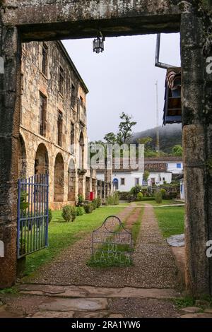 View through a stoney entrance gate to historic restored museum of  Sanctuary Caraça with arches and windows, Minas Gerais, Brazil Stock Photo