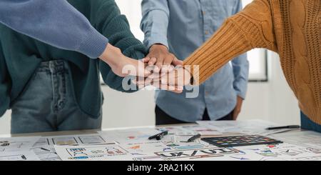 A close-up image of a team of developers or graphic designers putting their hands together at working table in office Stock Photo
