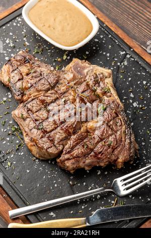 Grilled tomahawk steak on stone cutting board in steakhouse restaurant Stock Photo