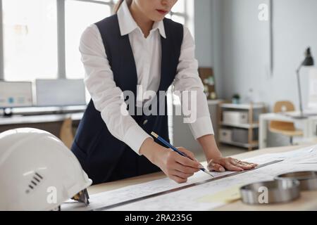 Closeup of female engineer drawing blueprints and plans at workstation in office, copy space Stock Photo