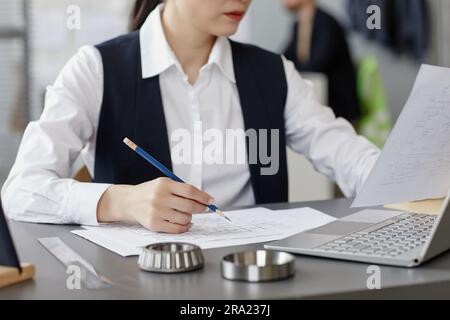 Closeup of female engineer using computer at workplace in office and designing blueprints Stock Photo