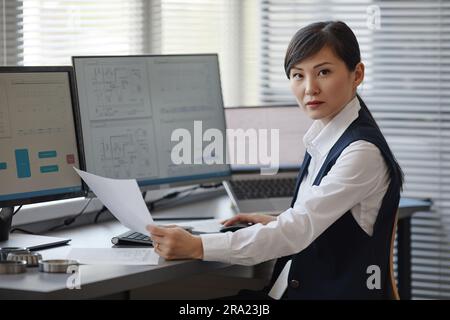 Portrait of Asian woman as female engineer using computer in office and looking at camera, copy space Stock Photo