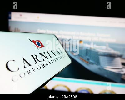 Cellphone with logo of cruise company Carnival Corporation plc on screen in front of business website. Focus on center of phone display. Stock Photo