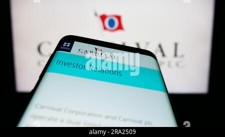 Mobile phone with website of cruise company Carnival Corporation plc on screen in front of business logo. Focus on top-left of phone display. Stock Photo