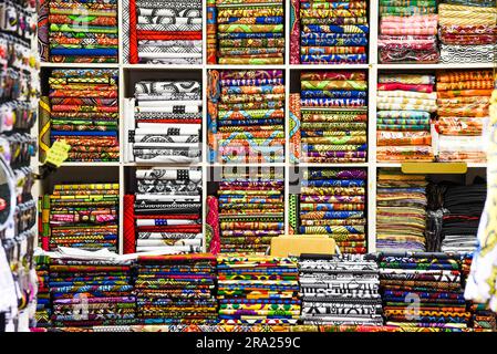 Different colored fabrics and clothes folded on a shelf in a store. Stock Photo