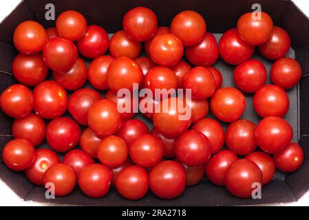 Top view of ripe cherry tomatoes in a cardboard box. Close up. Stock Photo