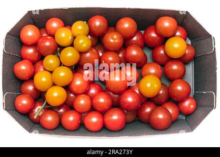 Red and yellow ripe cherry tomatoes in a cardboard box. Top view. Stock Photo