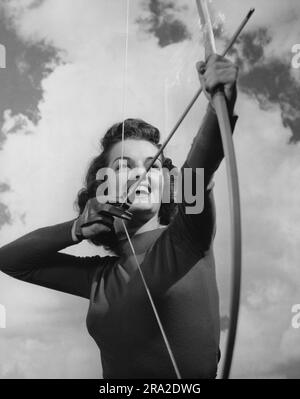 Young female archer pulling back the arrow about to shoot Stock Photo