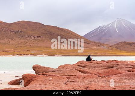 Tourist sitted in front of altiplanic lagoon at 'Piedras Rojas' park in Atacama desert Stock Photo