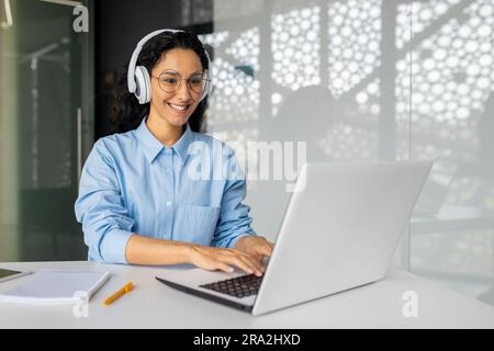 Young beautiful latin american programmer working inside office with laptop, woman coding new software security smiling and happy with achievement results. Stock Photo