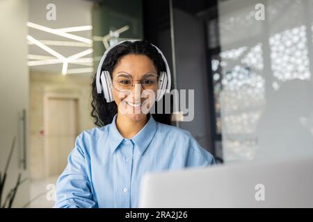 Young beautiful latin american programmer working inside office with laptop, woman coding new software security smiling and happy with achievement results. Stock Photo