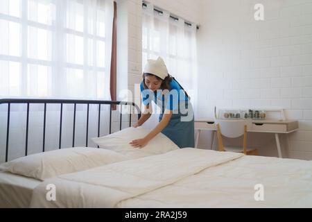 Asian woman housewife maid organizing pillow on the mattress on bed in the bedroom at home. Stock Photo