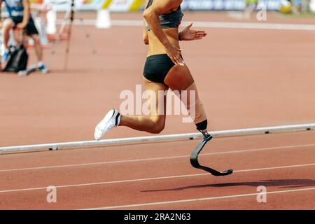 female para athlete on prosthetic leg running track stadium, summer para athletics championships Stock Photo