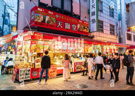 Night time in Chinatown, Kobe, Japan. Large Chinese take away food stall selling steamed buns and other foods, with people in front choosing. Stock Photo