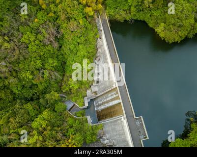 Aerial view of concrete dam and reservoir in green forest Stock Photo