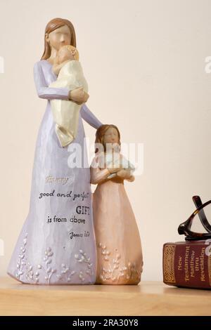 Christian themed ceramic ornament of a mother with her daughter and baby, inscibed with 'Every good and perfect gift is from above James 1:17'. Stock Photo