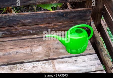 A small little green water can sits on the outdoor wooden deck full and ready to water plants and flowers in Missouri. Bokeh. Stock Photo