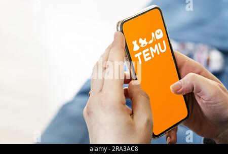 Boston, US, March 2023: Female hands holding a phone with Temu logo displayed on the screen. Temu is an online marketplace. Illustrative editorial Stock Photo
