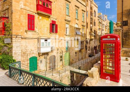 Valletta, Malta - The traditional Maltese street with red phone box, shutters and balconies and blue sky on a sunny day in the Capital city of Malta Stock Photo