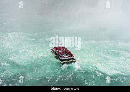 Niagara Falls boat tours attraction. Tourist people sailing on the travel boat close to the Niagara Horseshoe Fall at summer day. Canadian side view o Stock Photo