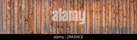 Panoramic wooden wall of a barn made of brown vertical, already weathered boards Stock Photo