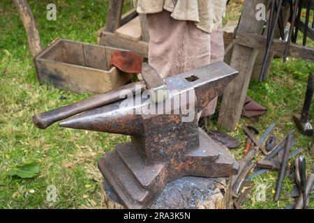 Blacksmith's anvil with hammer in the background with metal tools Stock Photo