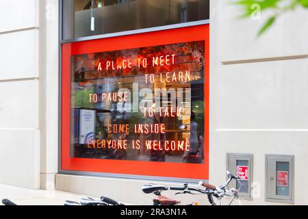 illuminated neon sign in window phrase a place to meet to learn to pause come inside everyone welcome] Stock Photo