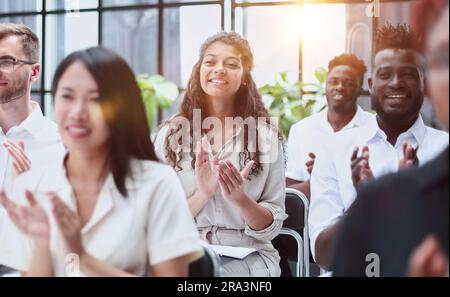 businesswoman applauding during seminar near interracial colleagues Stock Photo