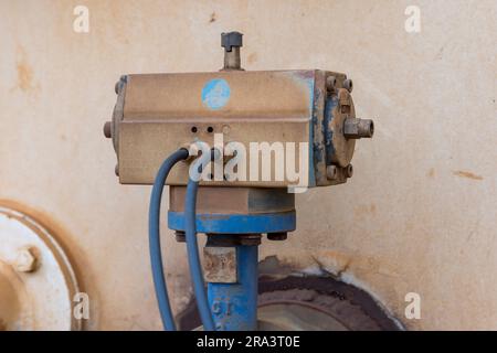 Photograph of an old and dirty motor controller on a water truck bolted to a blue steel flange and pipe with control cables connected Stock Photo