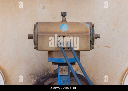 Photograph of an old and dirty motor controller on a water truck bolted to a blue steel flange and pipe with control cables connected Stock Photo