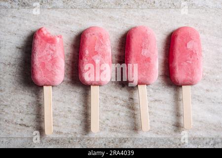Strawberry yogurt popsicles on a beige marble background. Stock Photo