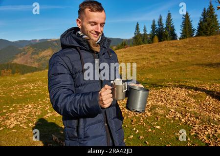 Tourist makes drip coffee against the backdrop of beautiful autumn mountains and nature Stock Photo