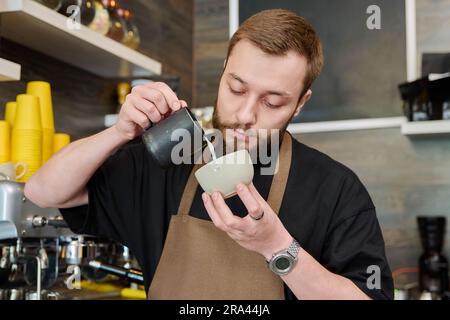 Young male barista preparing coffee in coffee shop Stock Photo
