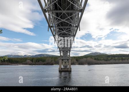 Johnsons Crossing, Teslin River steel Bridge on the Alaska Highway during spring summer time with cloudy, sky day and magnificent, huge structure Stock Photo