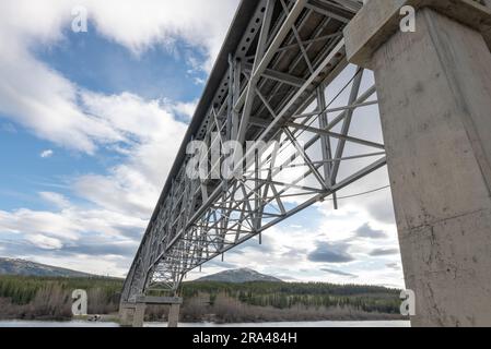 Johnsons Crossing, Teslin River steel Bridge on the Alaska Highway during spring summer time with cloudy, sky day and magnificent, huge structure Stock Photo