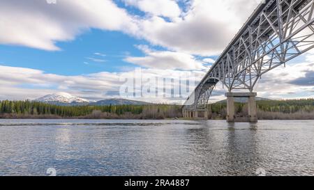 Johnsons Crossing, Teslin River steel Bridge on the Alaska Highway during spring summer time with cloudy, sky day and magnificent, huge structure Stock Photo