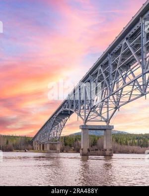 Johnsons Crossing, Teslin River steel Bridge on the Alaska Highway during spring summer time with cloudy, sky day and magnificent, huge structure Stock Photo