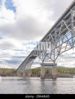 Johnsons Crossing, Teslin River steel Bridge on the Alaska Highway during spring summer time with cloudy, sky day and magnificent, huge structure Stock Photo