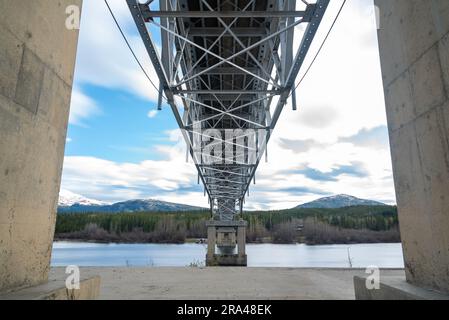 Johnsons Crossing, Teslin River steel Bridge on the Alaska Highway during spring summer time with cloudy, sky day and magnificent, huge structure Stock Photo