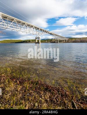 Johnsons Crossing, Teslin River steel Bridge on the Alaska Highway during spring summer time with cloudy, sky day and magnificent, huge structure Stock Photo