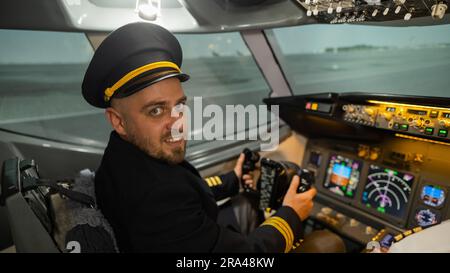 Caucasian bearded man smiling while sitting in a flight simulator. Pilot in the cockpit. Stock Photo